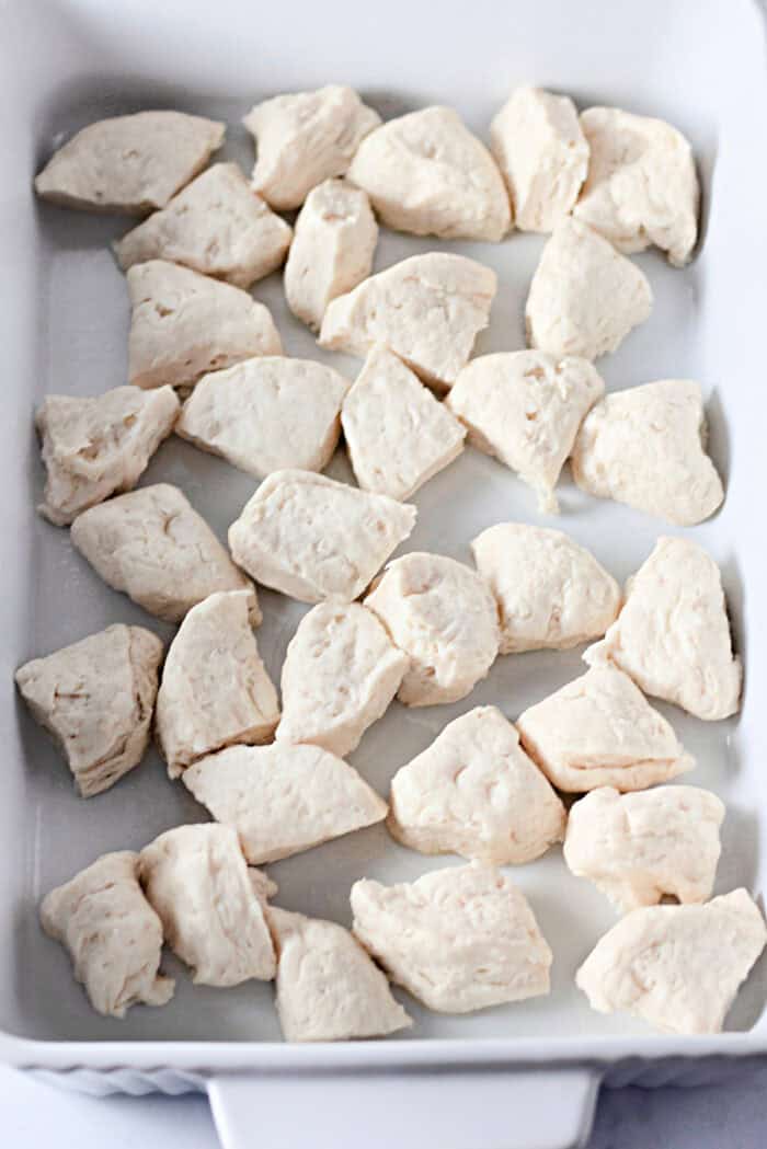 Quartered biscuits in the bottom of a casserole dish