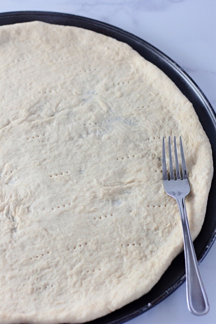 homemade pizza dough spread onto pizza pan